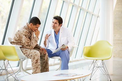 Physician speaking to a man in a military uniform in a clinical setting