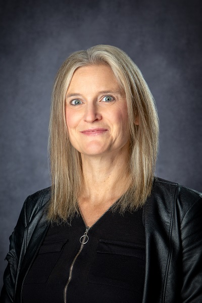a head and shoulders photo of a lady with blonde hair wearing a black and white checkered shirt 